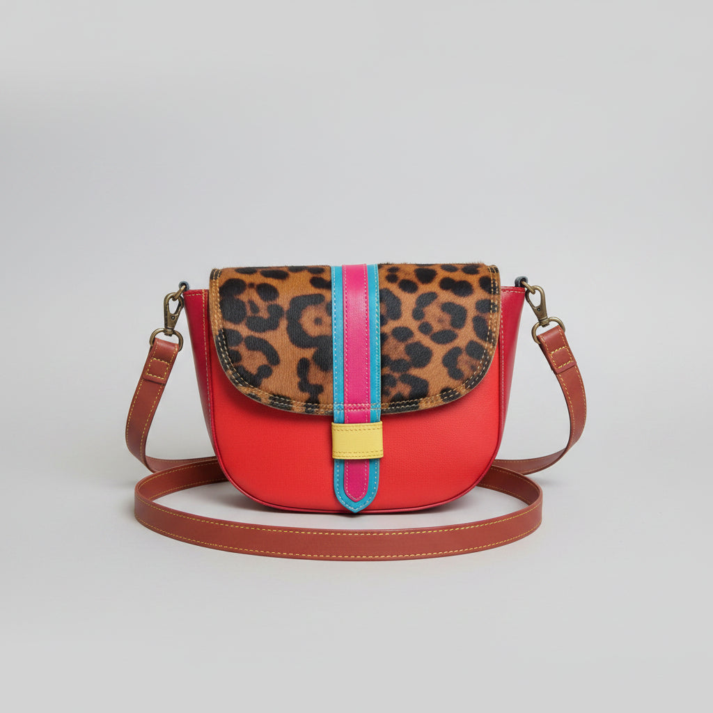 Handmade recycled leather crossbody bag in red and leopard print patchwork design with adjustable strap on a white background.