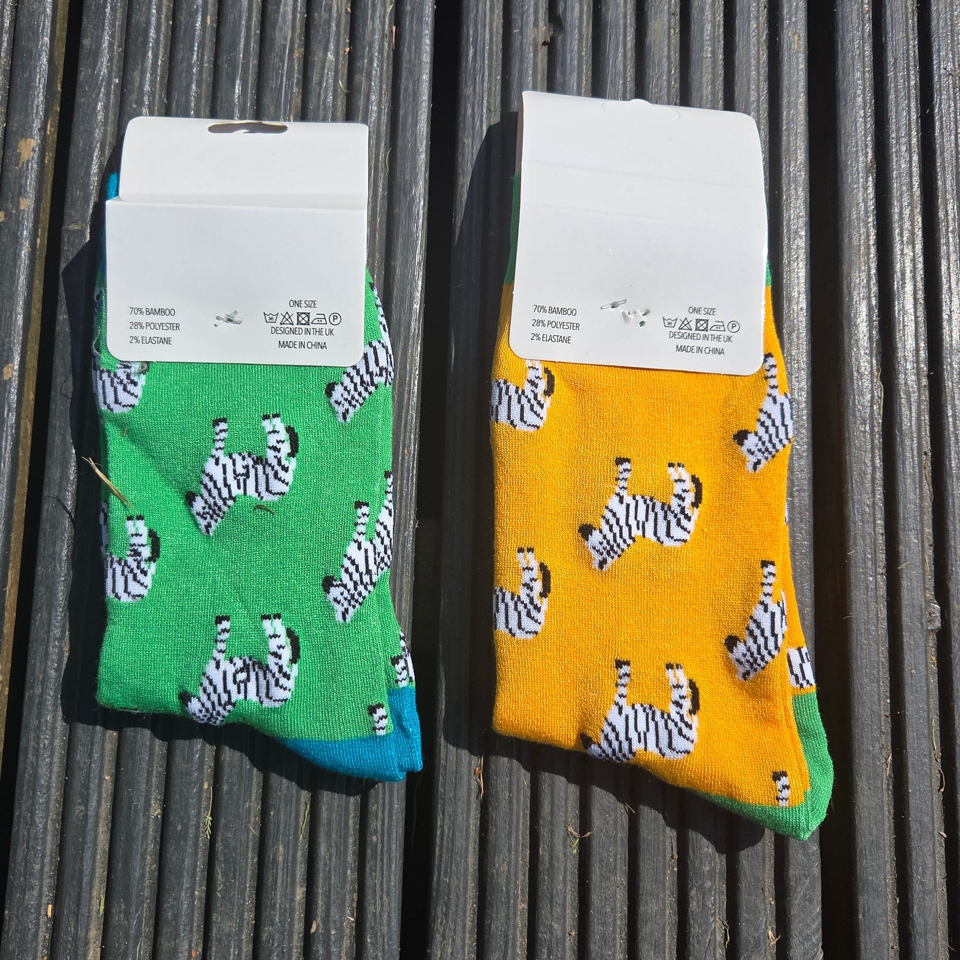 Two pairs of socks with zebra pattern packaging on a wooden surface