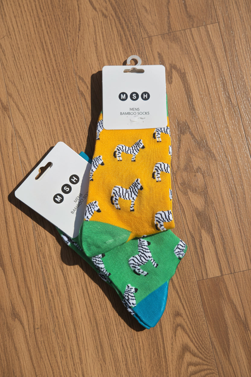 Two pairs of socks with zebra pattern on cardboard packaging against a wooden background