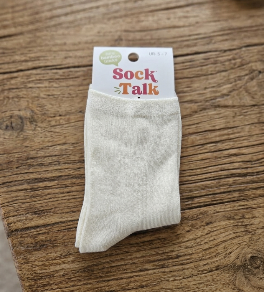 White bamboo socks with 'Sock Talk' packaging on a wooden surface