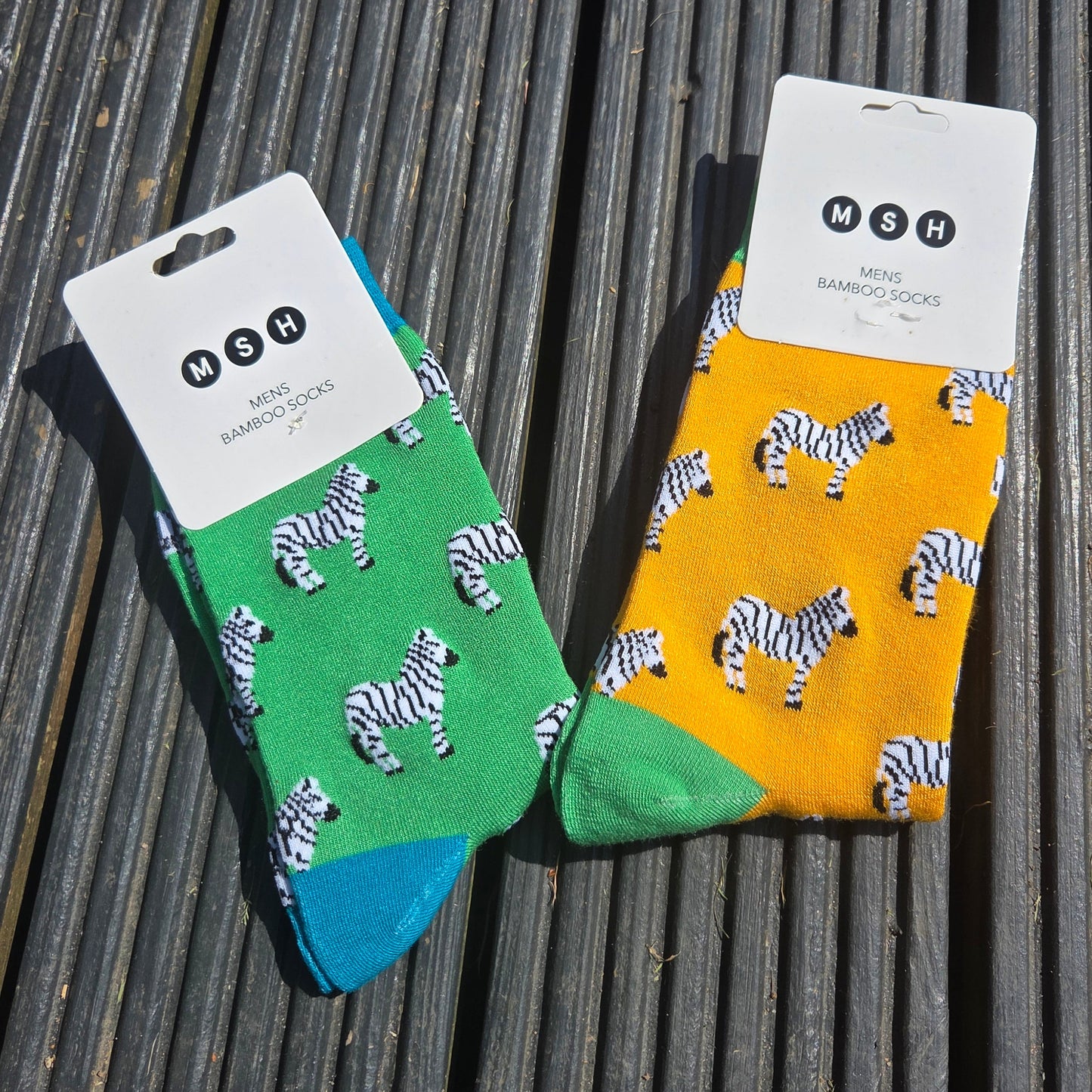 Two pairs of socks with zebra pattern with cardboard packaging on a textured surface